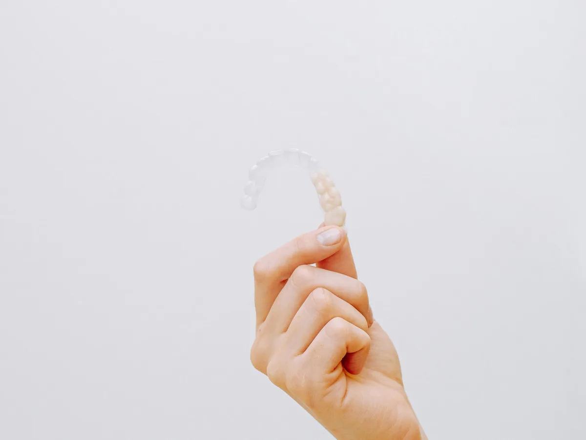 Clear aligner being held against a clean clinical background.