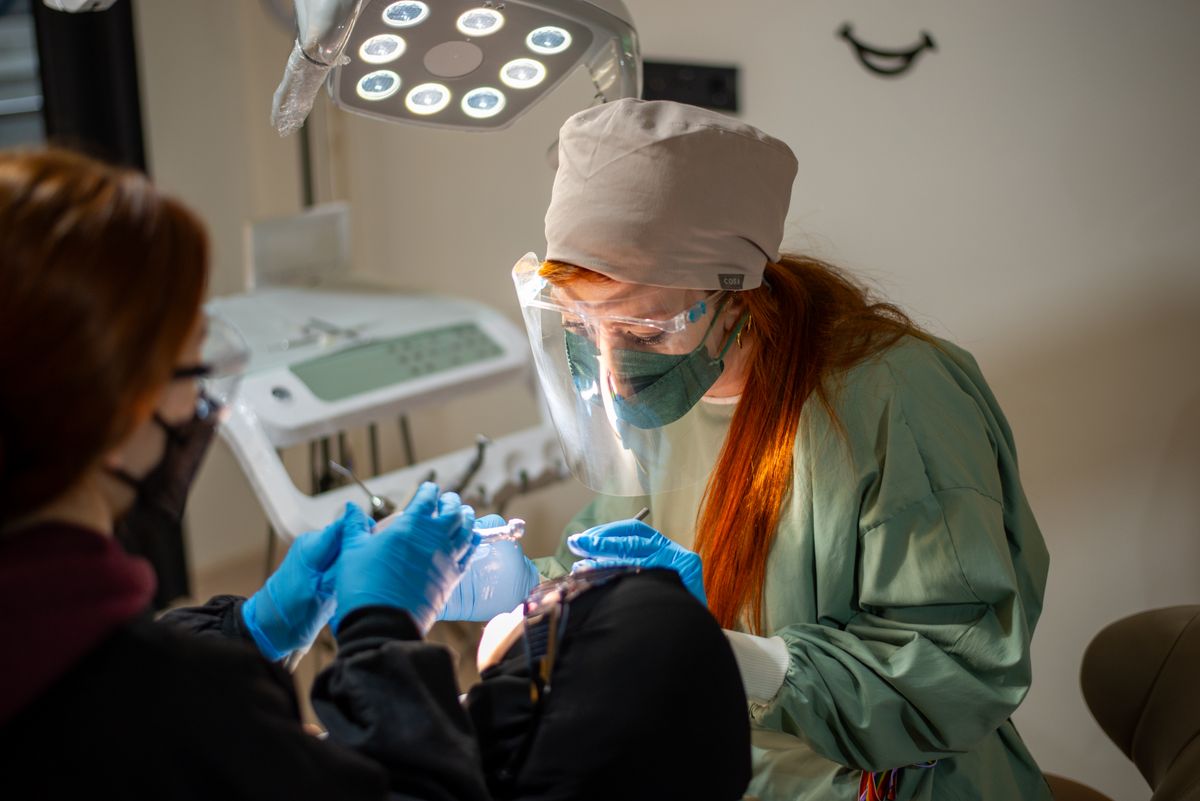 Dentist in surgical attire carrying out a dental procedure.