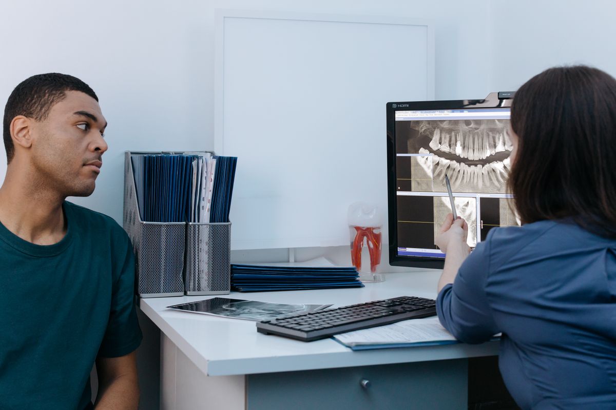 Dentist reviewing a dental X-ray with a patient; illustrative stock image.