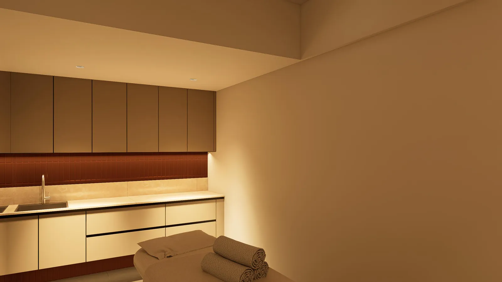 Treatment-bed room from the doorway with folded towels and integrated sink.