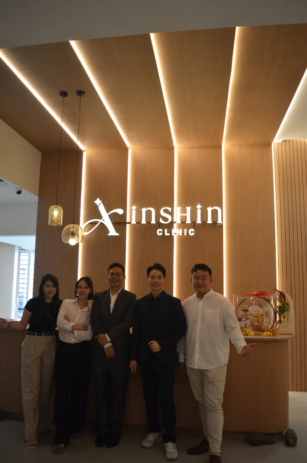 The Inshin Clinic team together beneath the illuminated clinic sign at reception.