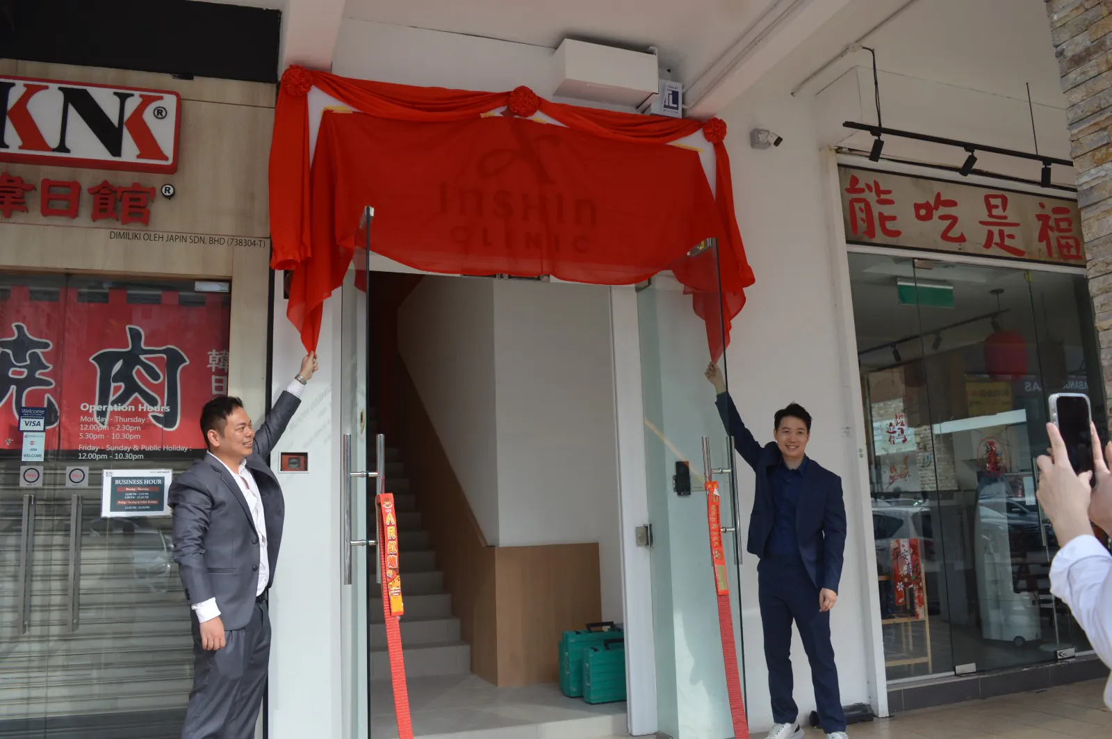 Two members of the Inshin Clinic team unveiling the clinic entrance on opening day.